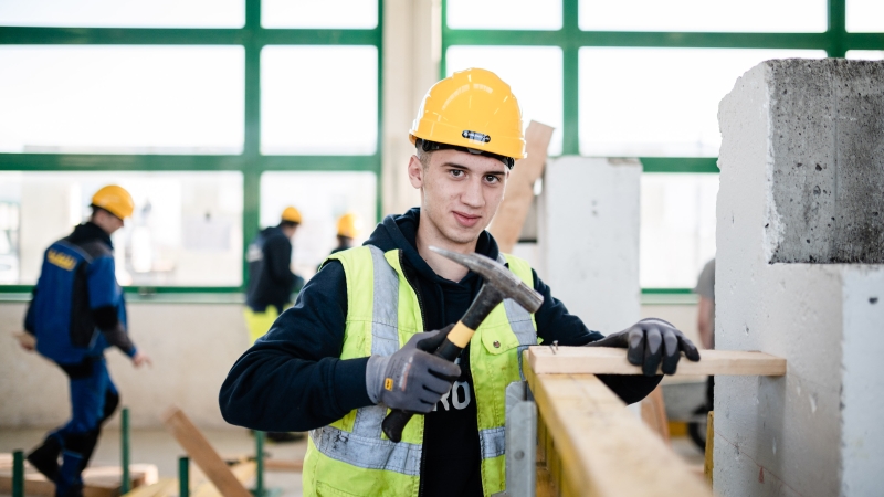 Lehrling mit Maurerhammer in Aktion Lehrling mit Maurerhammer in Aktion